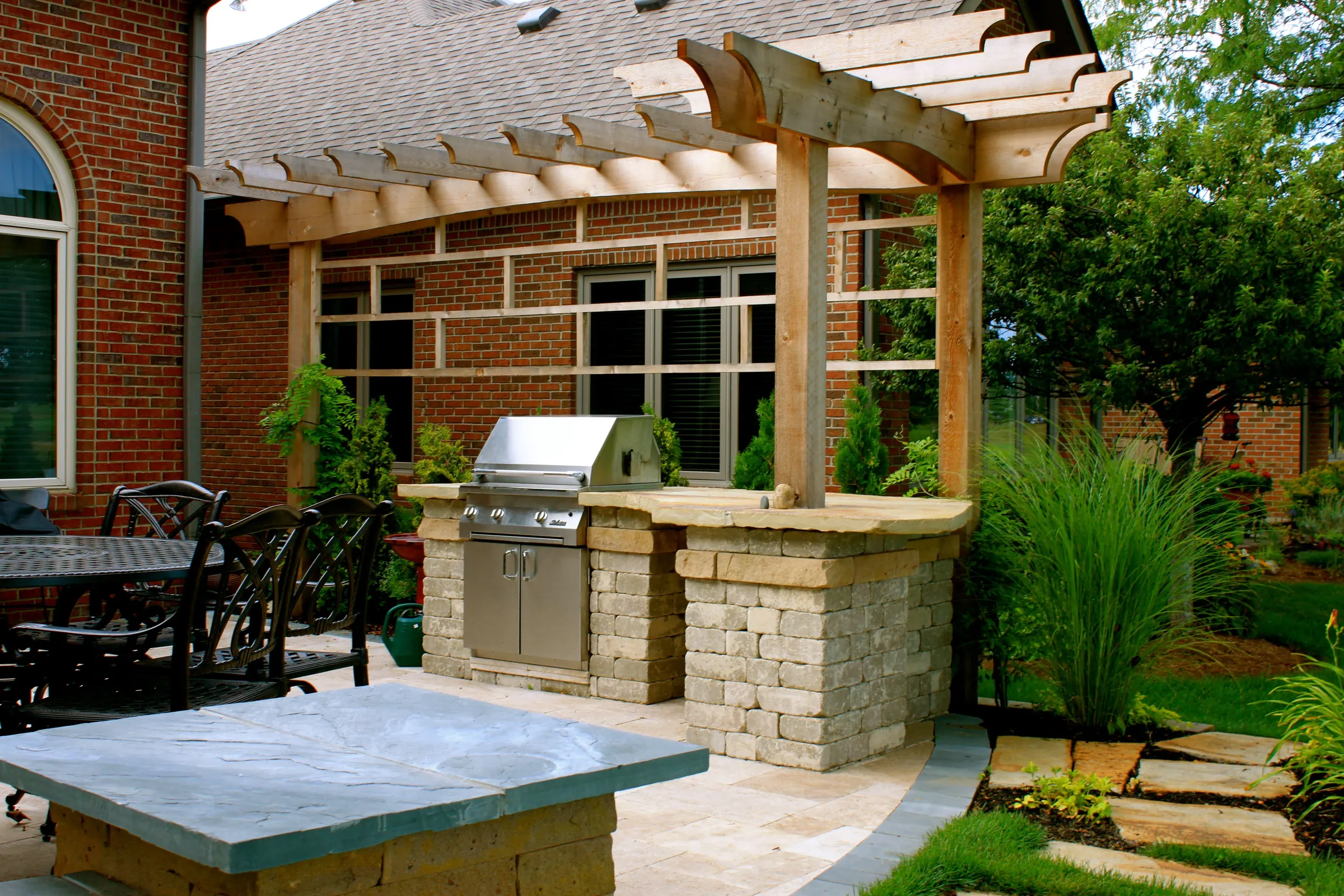 Outdoor kitchen with grill, pergola shade, paver, and flagstone.